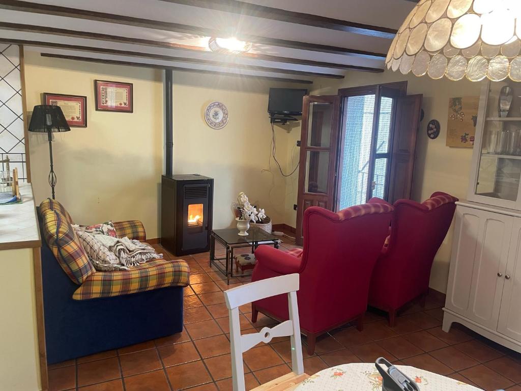 比利亞埃爾莫薩德爾里奧的住宿－CASA RURAL SAN JULIAN，客厅配有红色椅子和桌子