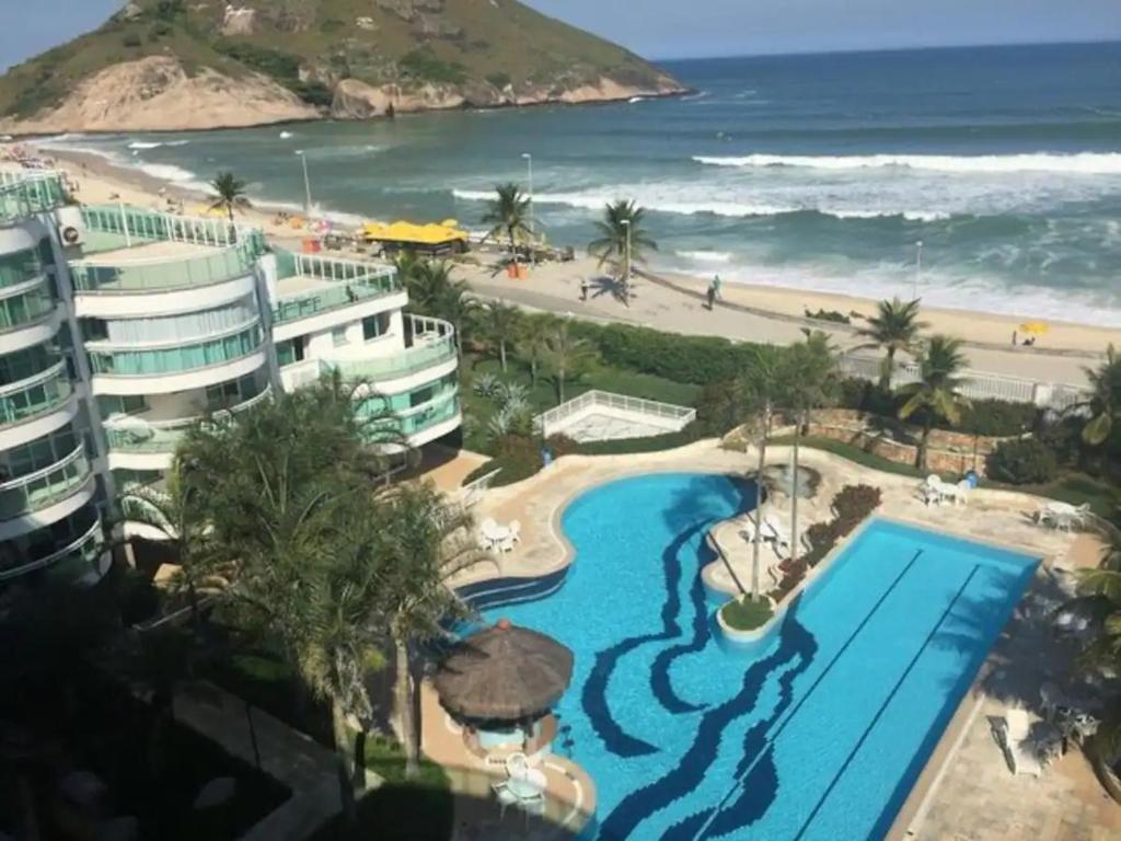 a view of a resort with a swimming pool and a beach at Maravilhoso flat em Pontal Beach Resort Recreio RJ in Rio de Janeiro