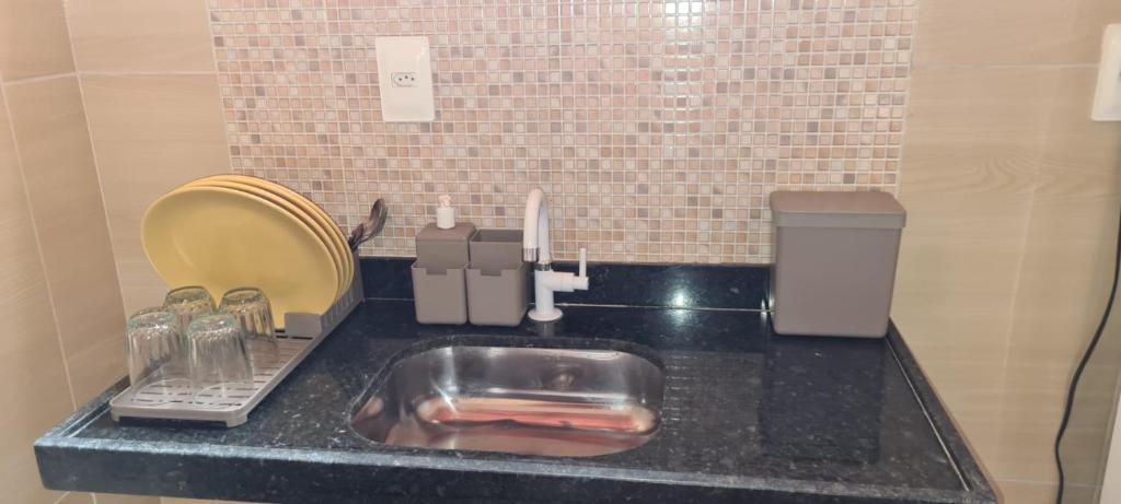 a bathroom counter with a sink with a mirror and a sponge at Chalés Caiçara Praia de Ponta Grossa in Icapuí