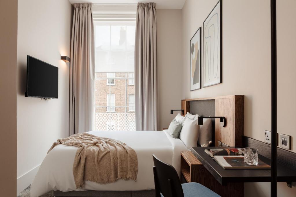 a hotel room with a bed and a desk and a window at Sonder The Earl in Dublin