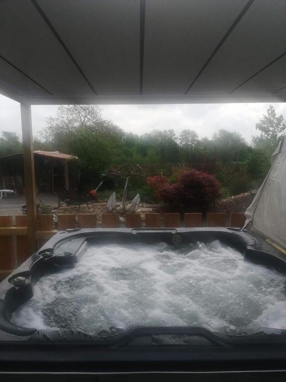 a jacuzzi tub with a view of a yard at Gite wellness Au champ du bouillon proche de Pairi Daiza et de la ville Ath 