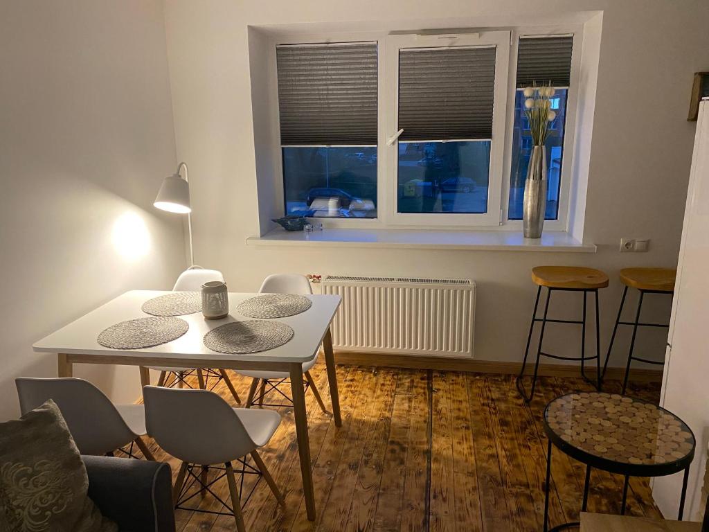 d'un salon avec une table, des chaises et une fenêtre. dans l'établissement R.R. Liepaja Apartments Klaipedas, à Liepāja
