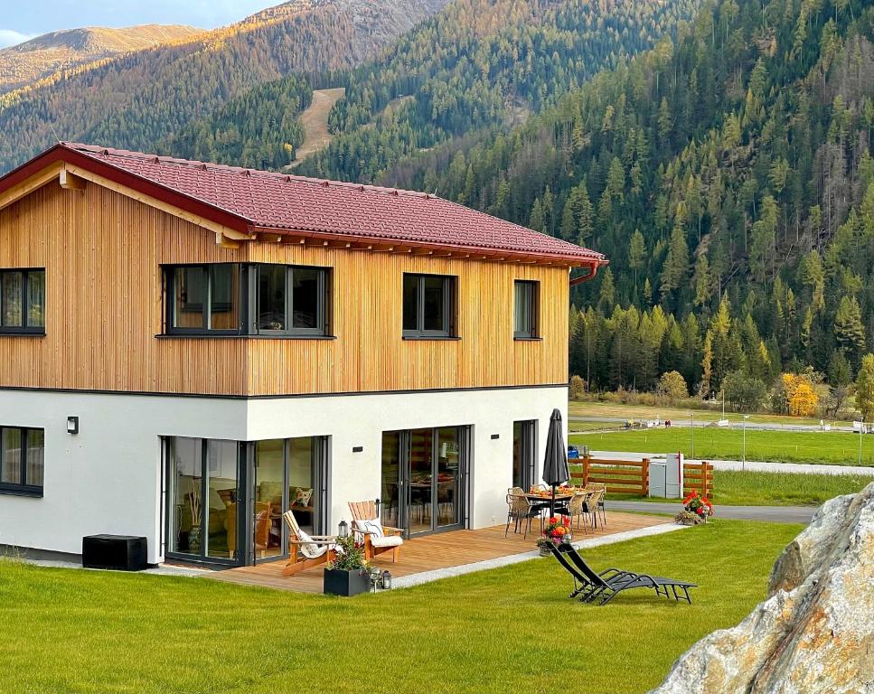 ein großes Haus mit einer Terrasse und einem Berg in der Unterkunft TYROL PURElife Lodges in Sankt Jakob in Defereggen