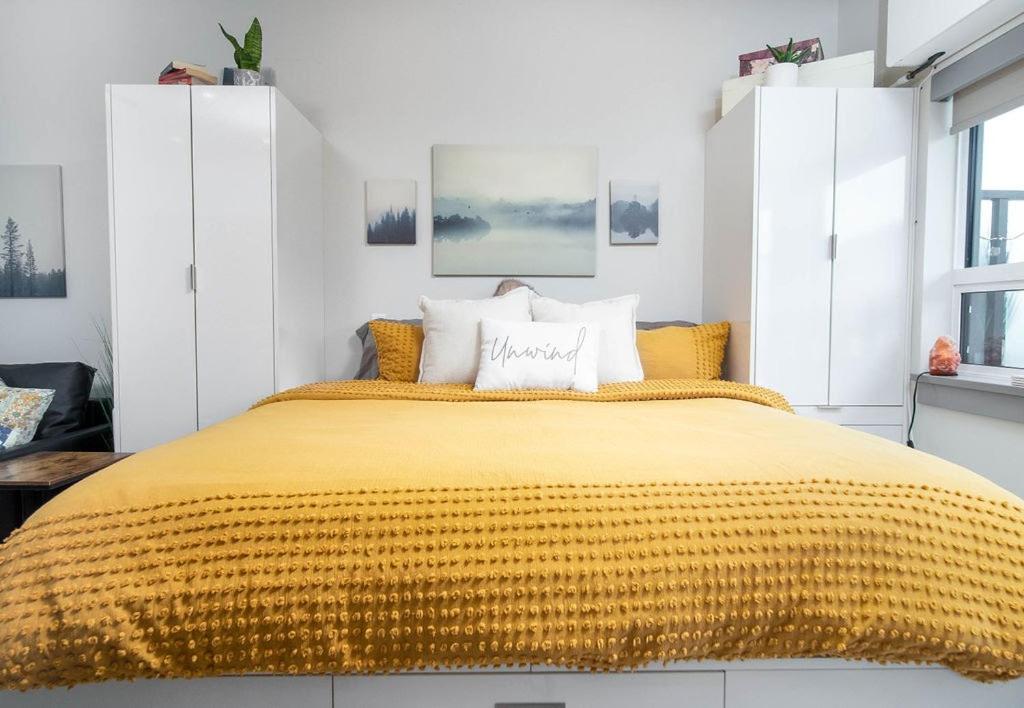 a bedroom with a large bed with a yellow blanket at Top Floor on Okanagan Lake with AC & Heated Pool in Vernon