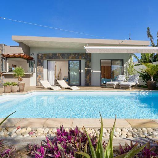 einen Pool mit Stühlen und ein Haus in der Unterkunft Villa Primera 3 bedroom bungalow with private pool Grand Bay in Grand Baie