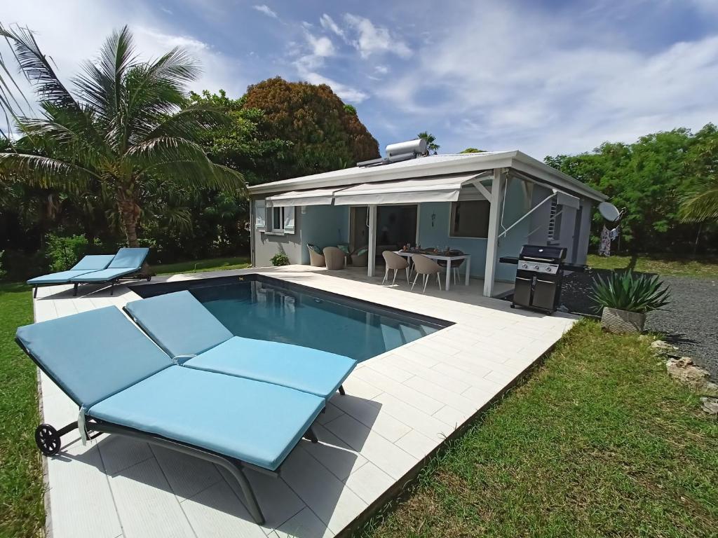 ein Pool mit zwei blauen Stühlen und ein Haus in der Unterkunft Villa 4 étoiles avec piscine, 3 chambres et jardin tropical in Saint-François
