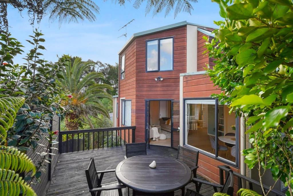 a house with a wooden deck with a table and chairs at Elegant 2BR Family Home - Aircon - 5min to Beach in Auckland