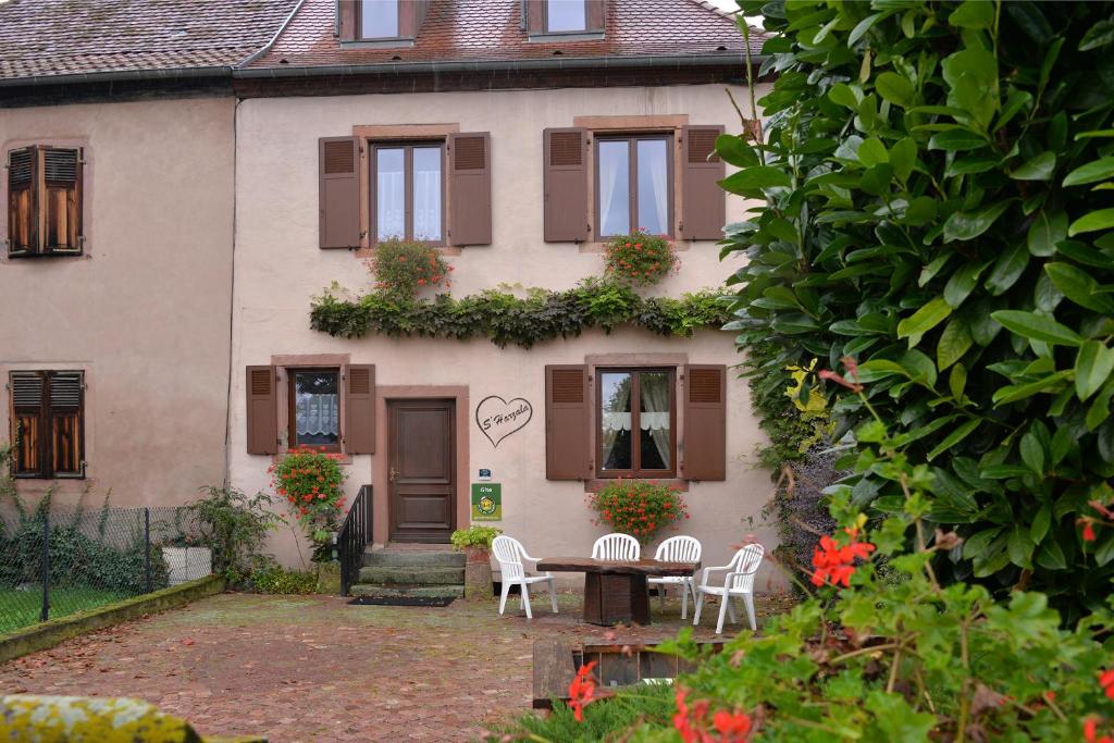 una casa con una mesa y sillas frente a ella en S'Harzala Rouge, en Bergheim