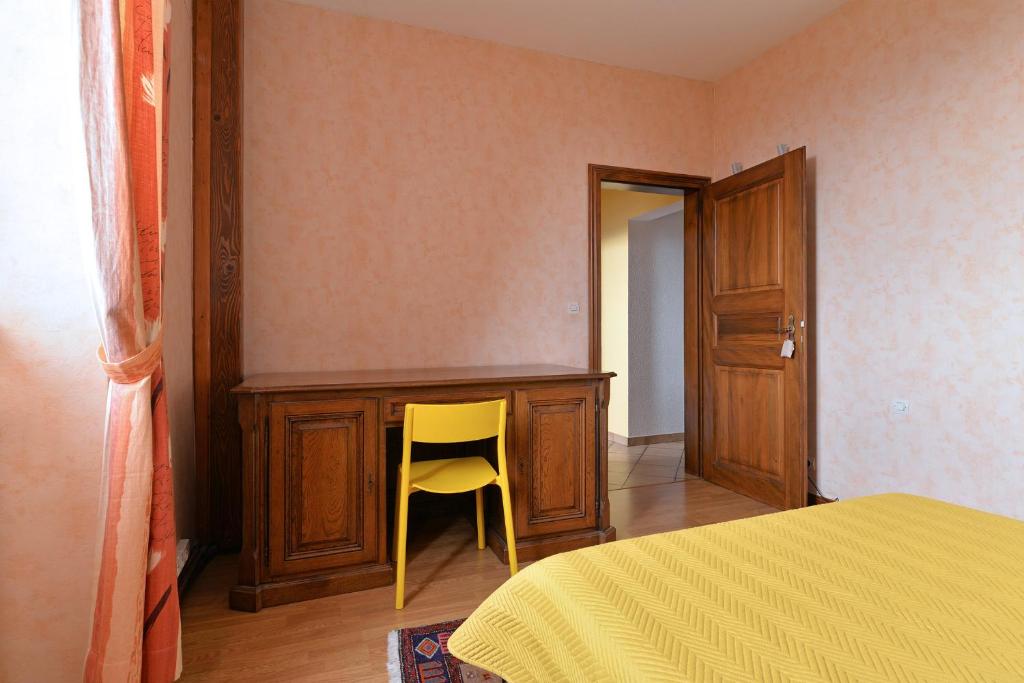 a bedroom with a desk and a yellow chair next to a bed at S&#39;Harzala Jaune in Bergheim