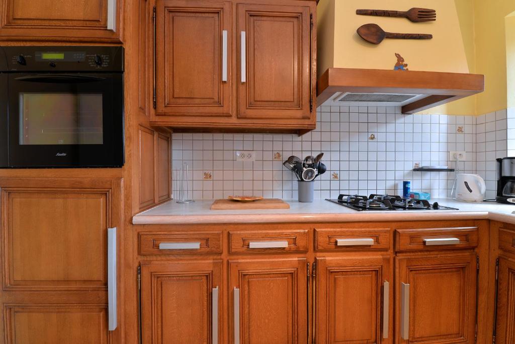 a kitchen with wooden cabinets and a stove top oven at S&#39;Harzala Jaune in Bergheim