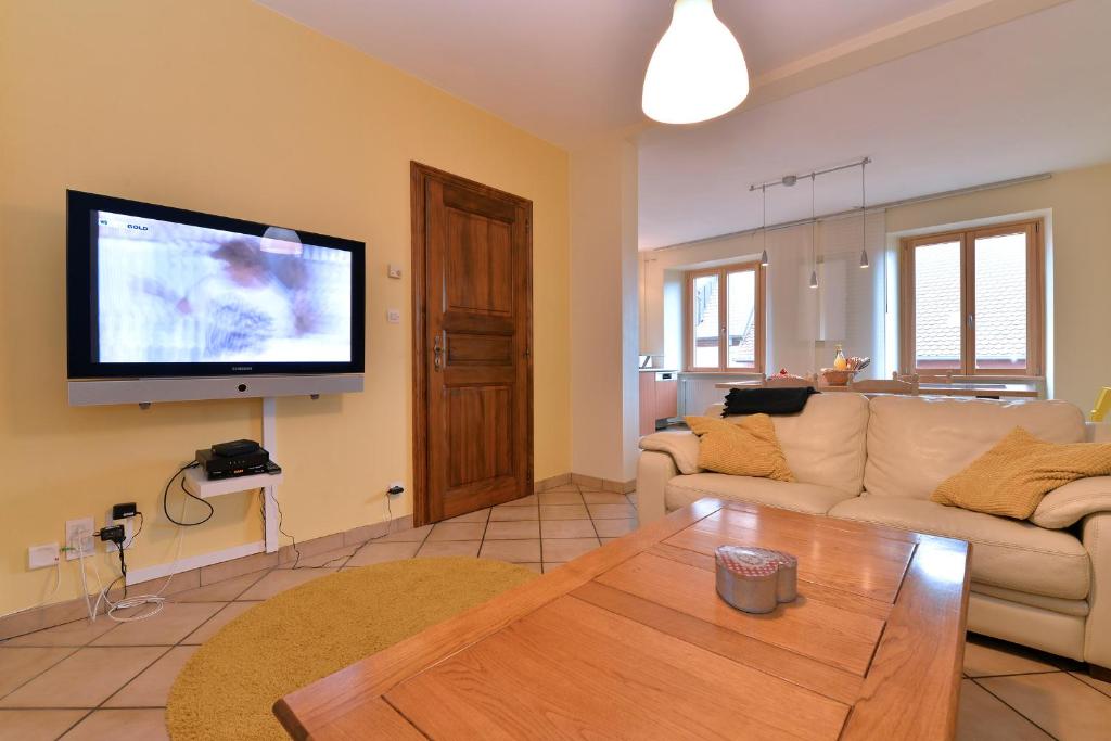 a living room with a couch and a tv on the wall at S&#39;Harzala Jaune in Bergheim