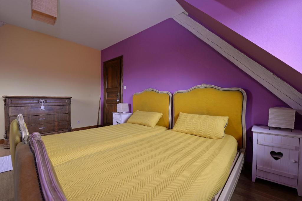 a bedroom with a yellow bed with a purple wall at S&#39;Harzala Jaune in Bergheim