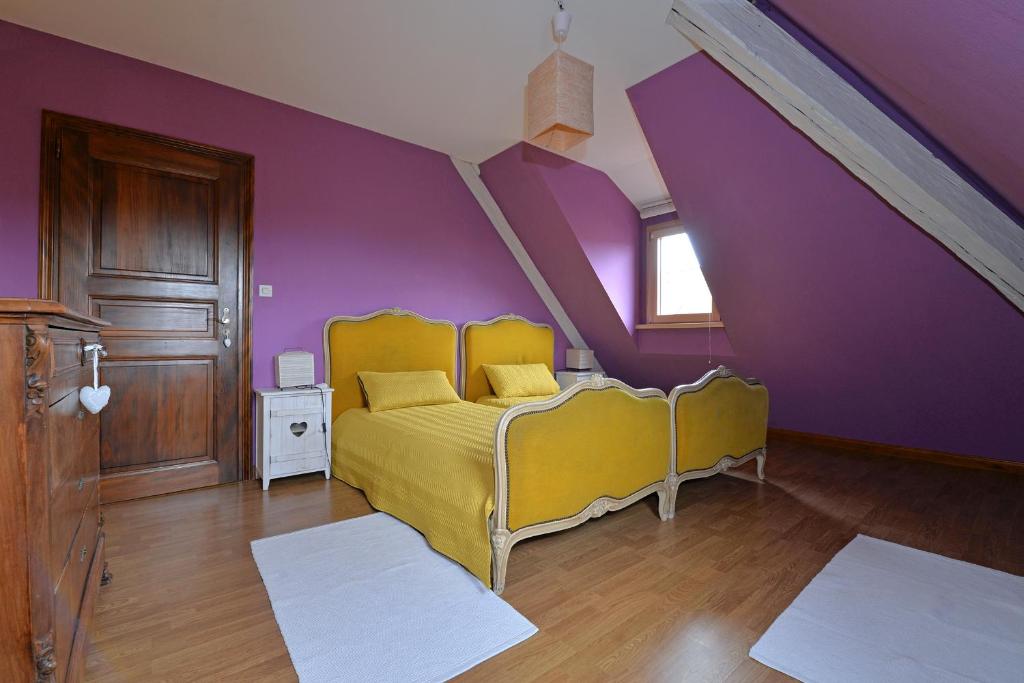 a bedroom with a yellow bed and purple walls at S&#39;Harzala Jaune in Bergheim