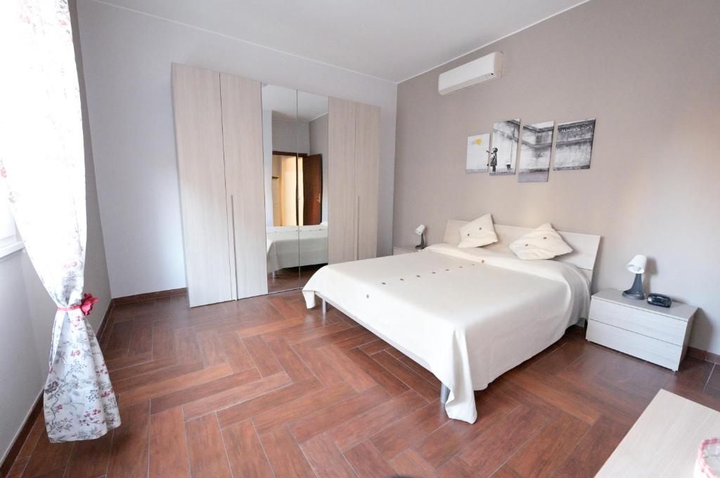 a bedroom with a white bed and a wooden floor at Appartamento centrale in Lido di Ostia