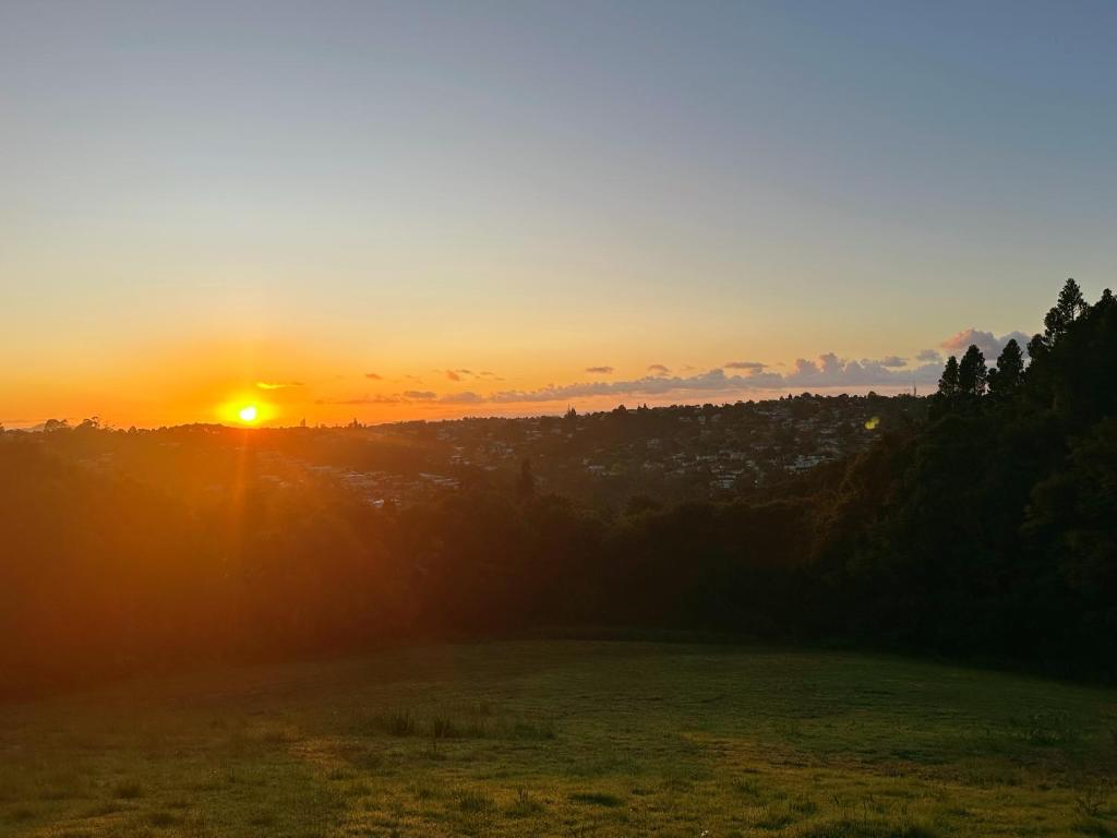 a sunset over a field with the sun setting in the background at Echo Lodge in Auckland