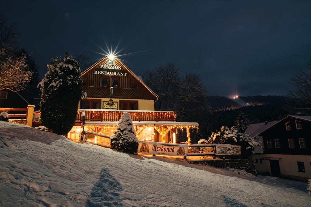 a large building with lights on it in the snow at Pension & Restaurant Krakonoš in Harrachov