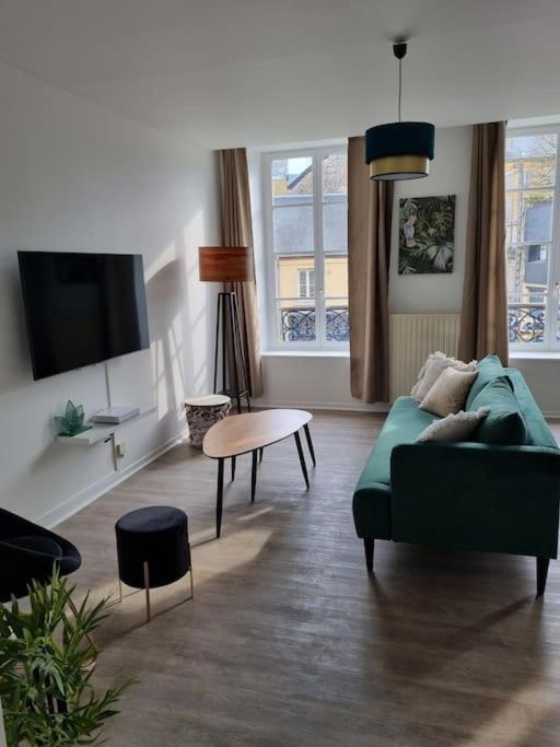 un salon avec un canapé vert et une table dans l'établissement Appartement Jungle- hypercentre -Charleville, à Charleville-Mézières