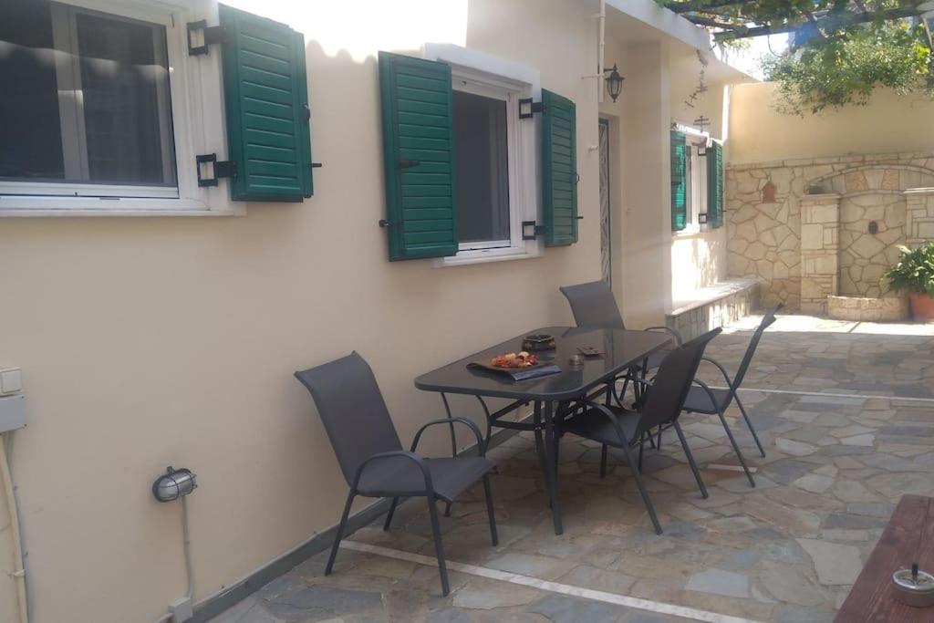un tavolo e sedie in un patio con persiane verdi di Detached house with a lovely yard 5' walk from Metro Station Agios Dimitrios and METRO MALL ad Atene