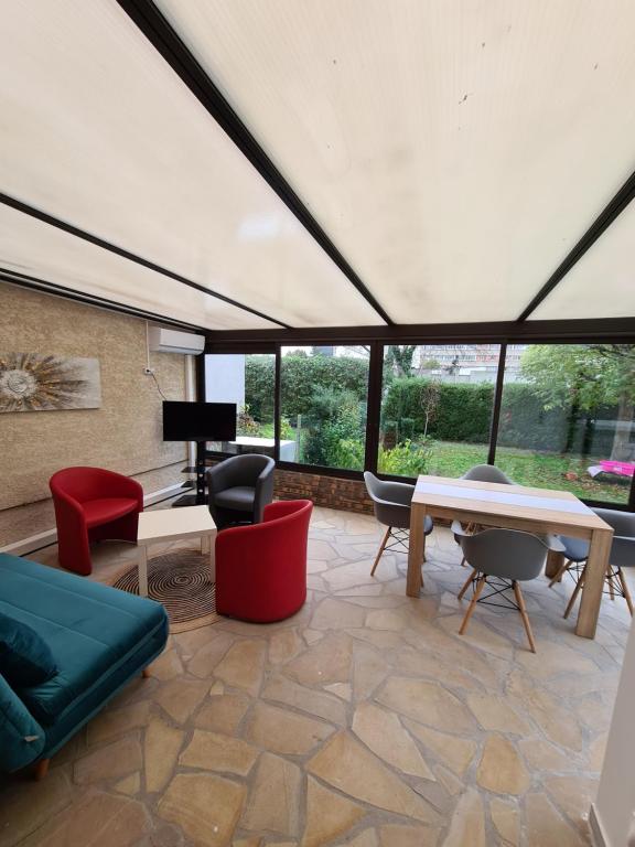 een woonkamer met veel meubilair en ramen bij Studio entièrement équipé avec véranda commune in Neuilly-sur-Marne