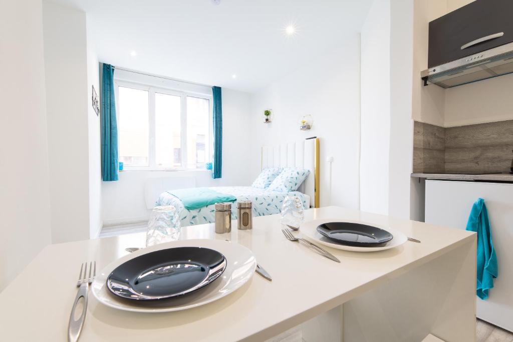 a white kitchen with two plates on a counter at Glm Residences 1 in Saint-Quentin