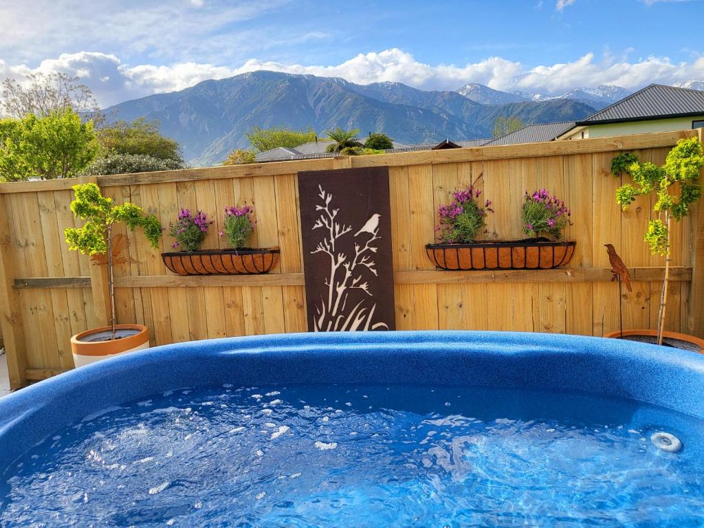 a hot tub in a yard with a fence and flowers at Te Mahuru Retreat in Kaikoura