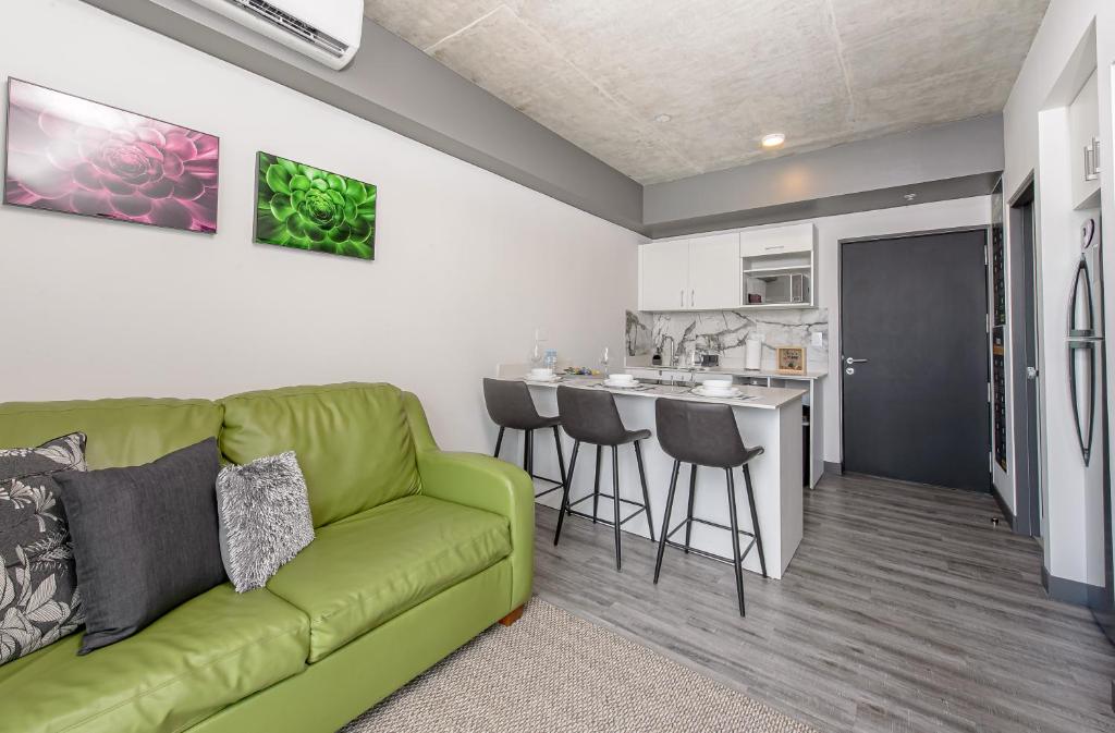 a living room with a green couch and a kitchen at San José Apt with Fantastic Views, Parking and Air Conditioning in San José