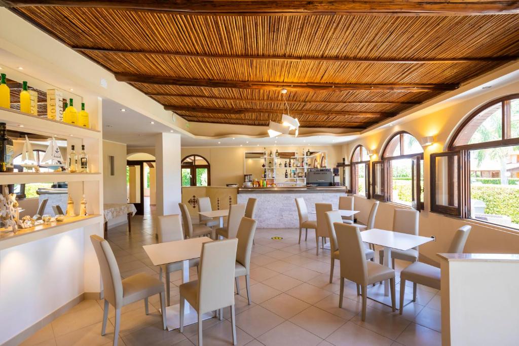 restauracja ze stołami i krzesłami oraz kuchnia w obiekcie Hotel La Fattoria Sul Mare w mieście Capo Vaticano