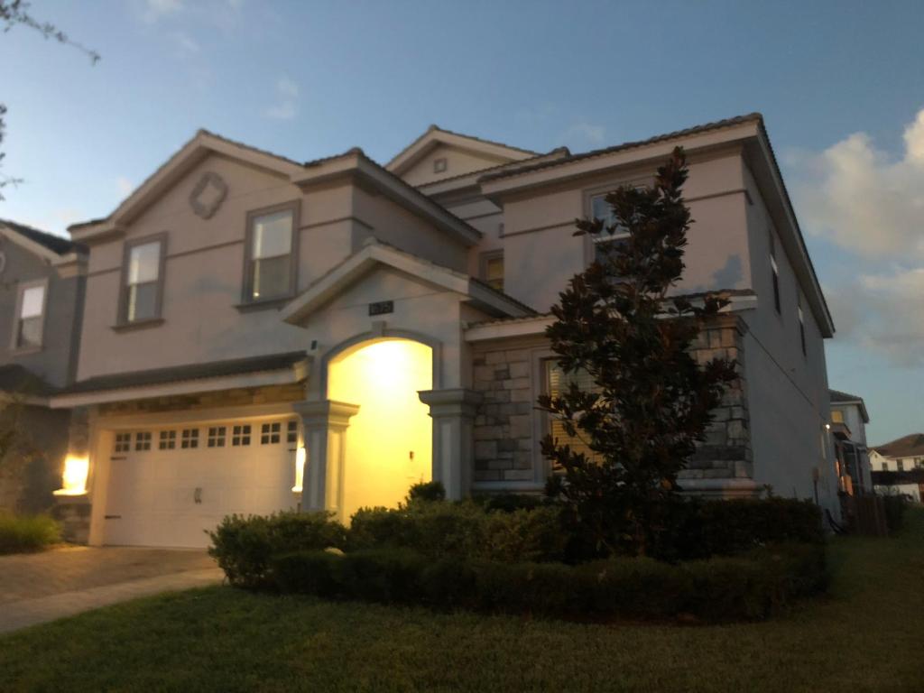 a large house with a garage at dusk at 8 bedrooms, 5 bathrooms. Theater Room + Pool/Spa + WiFi in Davenport