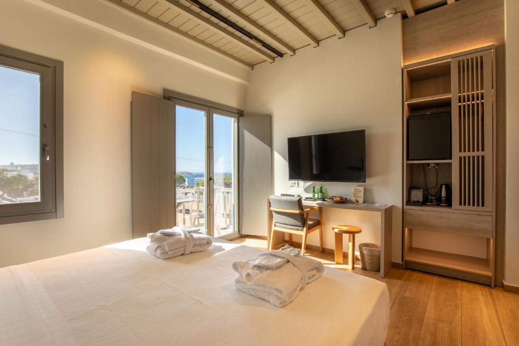 a bedroom with a bed with a television and a desk at Fabrikas in Mikonos