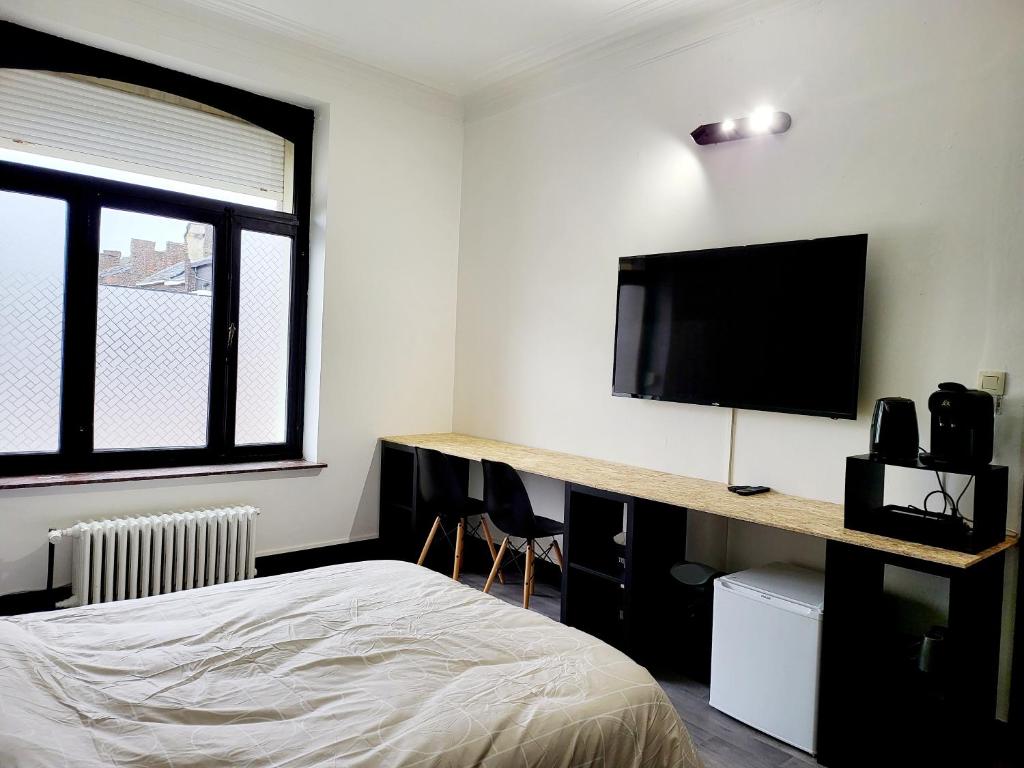 een slaapkamer met een bed en een flatscreen-tv bij Private industrial room in center of Charleroi in Charleroi