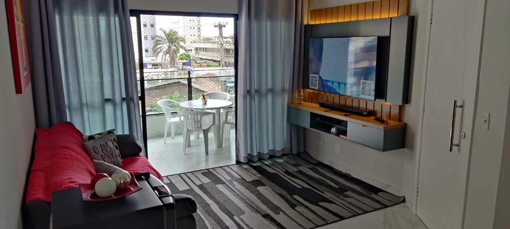 sala de estar con sofá y TV de pantalla plana en Apartamento Guarujá Astúrias en Guarujá