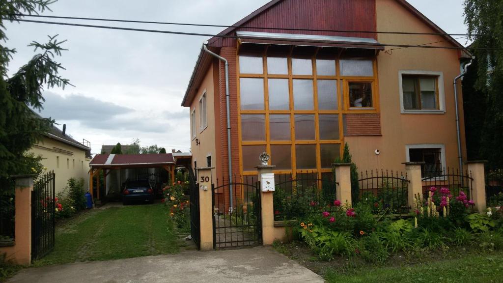 ein Haus mit einem großen Fenster und einem Zaun in der Unterkunft Brigitta vendégház in Egerszalók