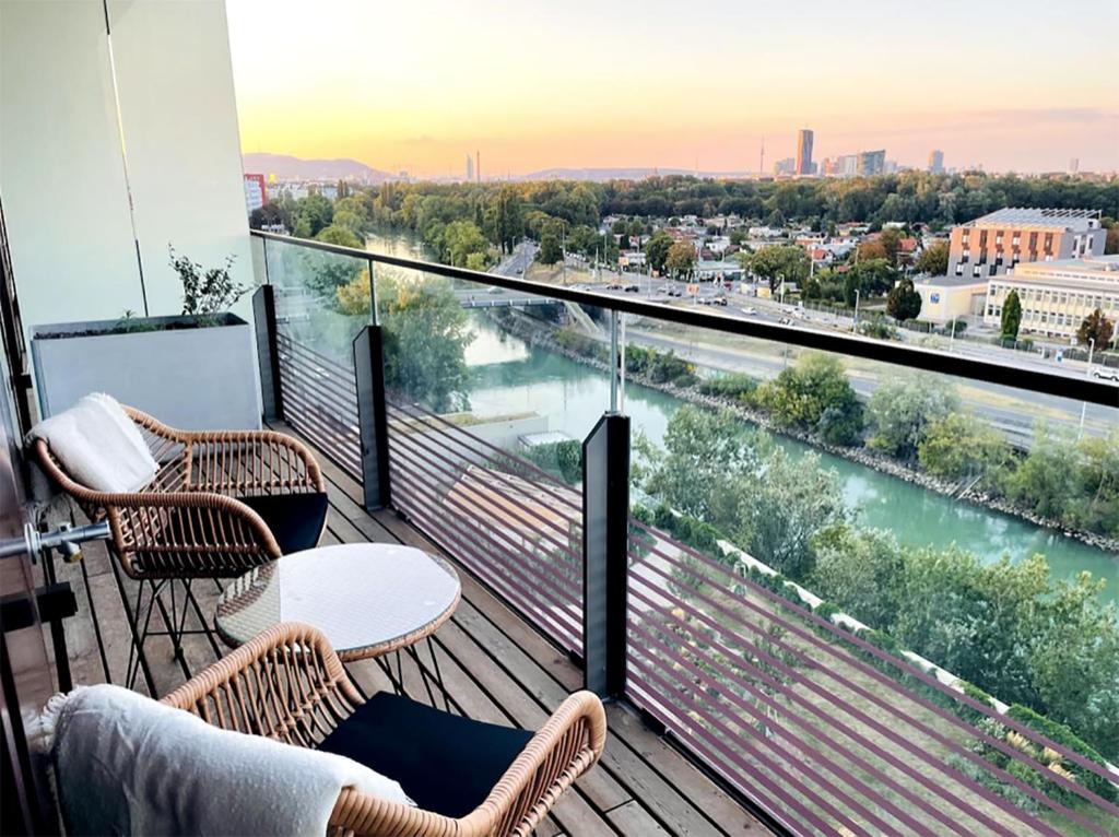a balcony with two chairs and a view of a river at Sunrise above sky with ROOFTOP Pool and FREE parking in Vienna