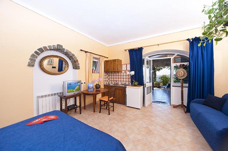 sypialnia z niebieskim łóżkiem i kuchnią w obiekcie Appartamenti Bellavista w mieście Ischia