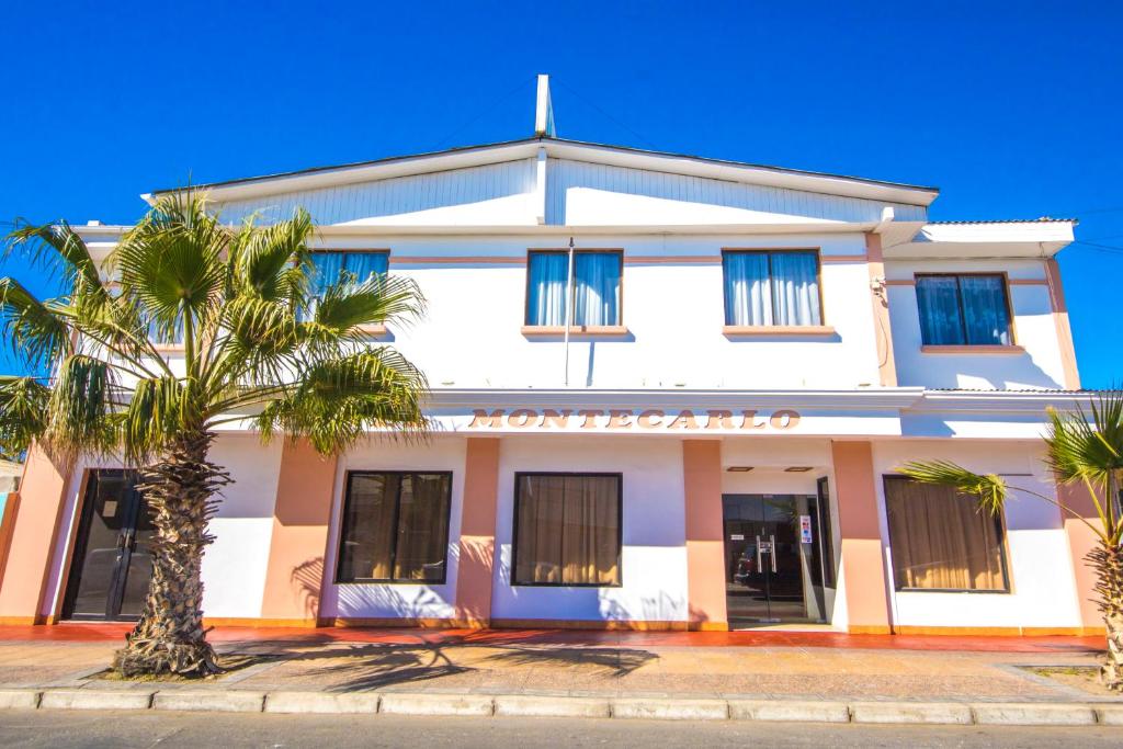 um edifício branco com uma palmeira em frente em Hotel Montecarlo em Caldera