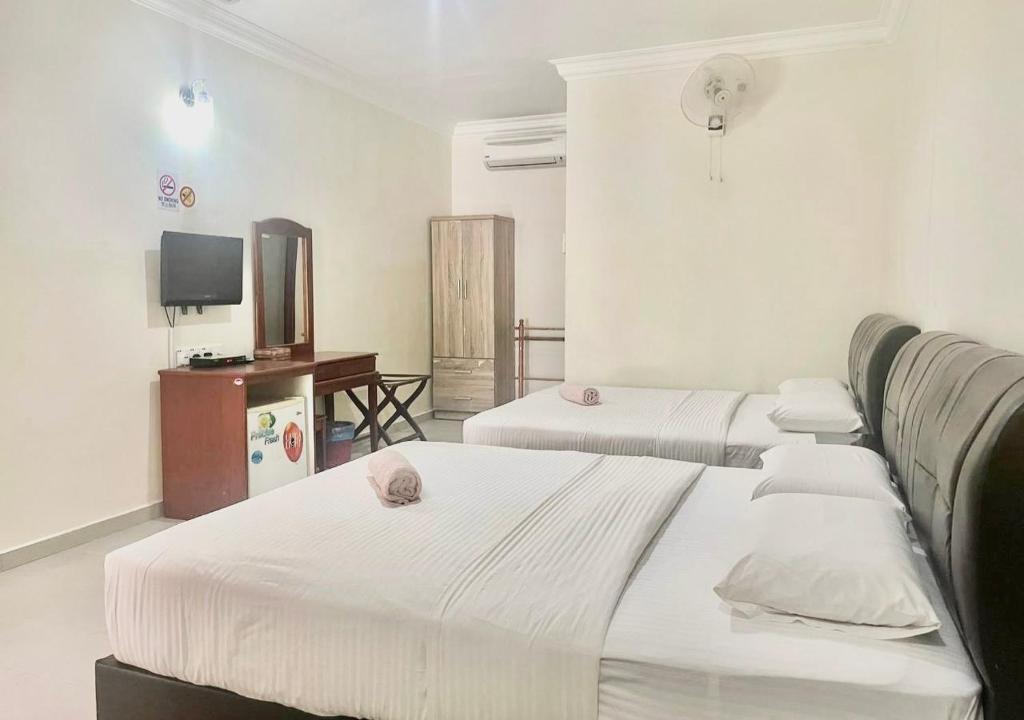a hotel room with two beds and a television at Kenangan Inn in Pantai Cenang