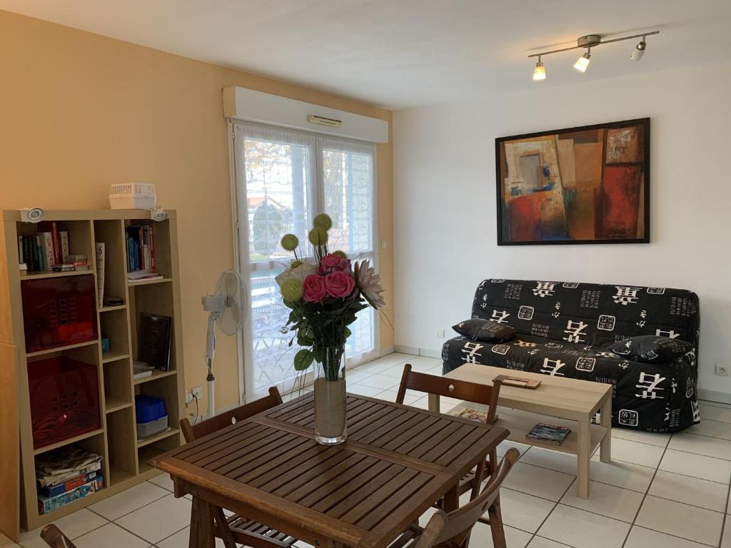 un salon avec une table avec un vase de fleurs dans l'établissement Appartement Cosy à Biscarrosse - 4 Pers, Centre-Ville, Parking, Balcon, Ménage Inclus - FR-1-319-445, à Biscarrosse