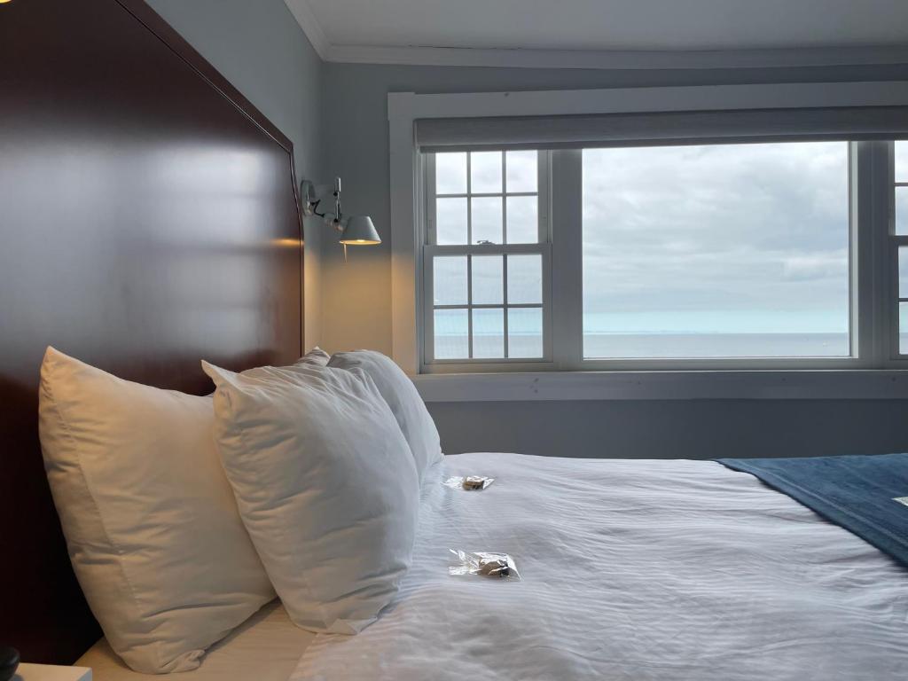 a bed with white sheets and pillows in front of a window at Emerson Inn By The Sea in Rockport