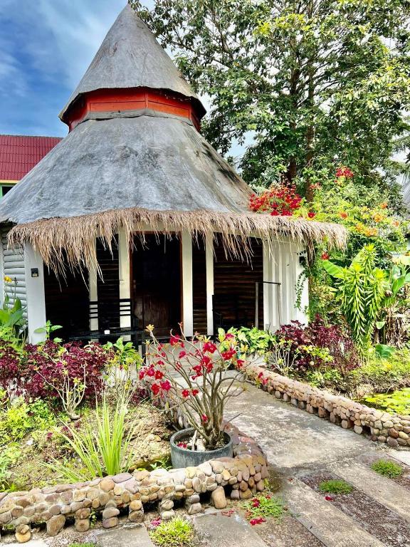 a small hut with a thatched roof in a garden at M'pay Bay Guesthouse in Koh Rong Sanloem