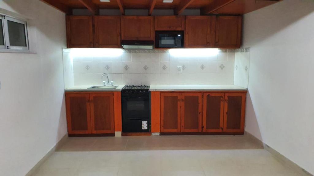 a small kitchen with wooden cabinets and a sink at Casa Quinta La Gualeya in Gualeguay
