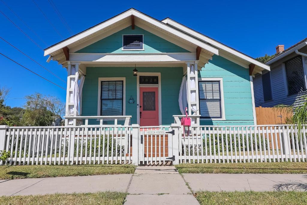 una casa azul con una valla blanca en The Old Flamingo Vibrant Bungalow just 2 mins from the beach, en Galveston