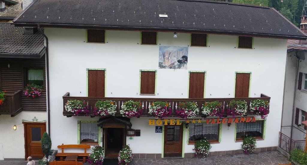 ein weißes Gebäude mit einem Balkon und Blumen darauf in der Unterkunft Albergo Valgranda in Alleghe