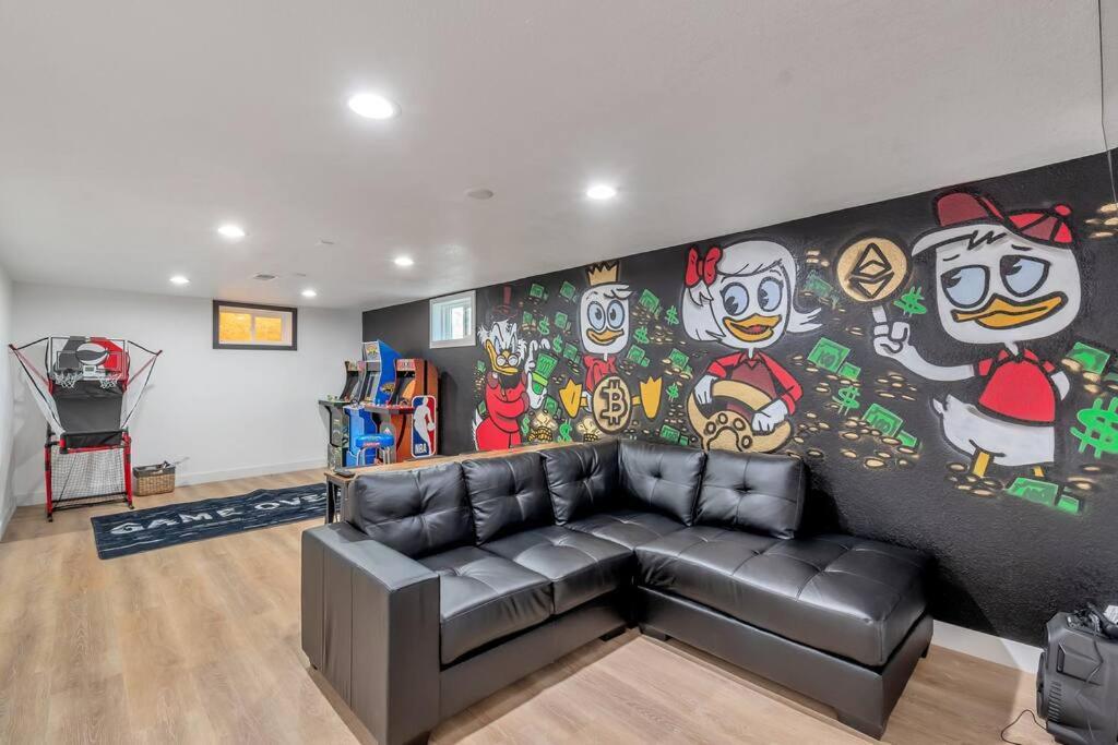 a living room with a black leather couch in front of a mural at Renovated 4br w/game room to entertain Near DT in Lakewood
