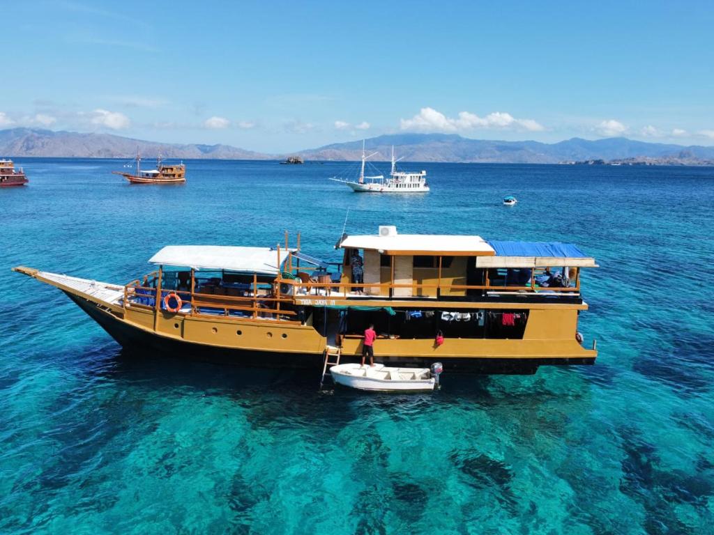 a yellow boat in the water with a small boat at Liveaboard komodo Tour 2Days 1Night share trip in Labuan Bajo
