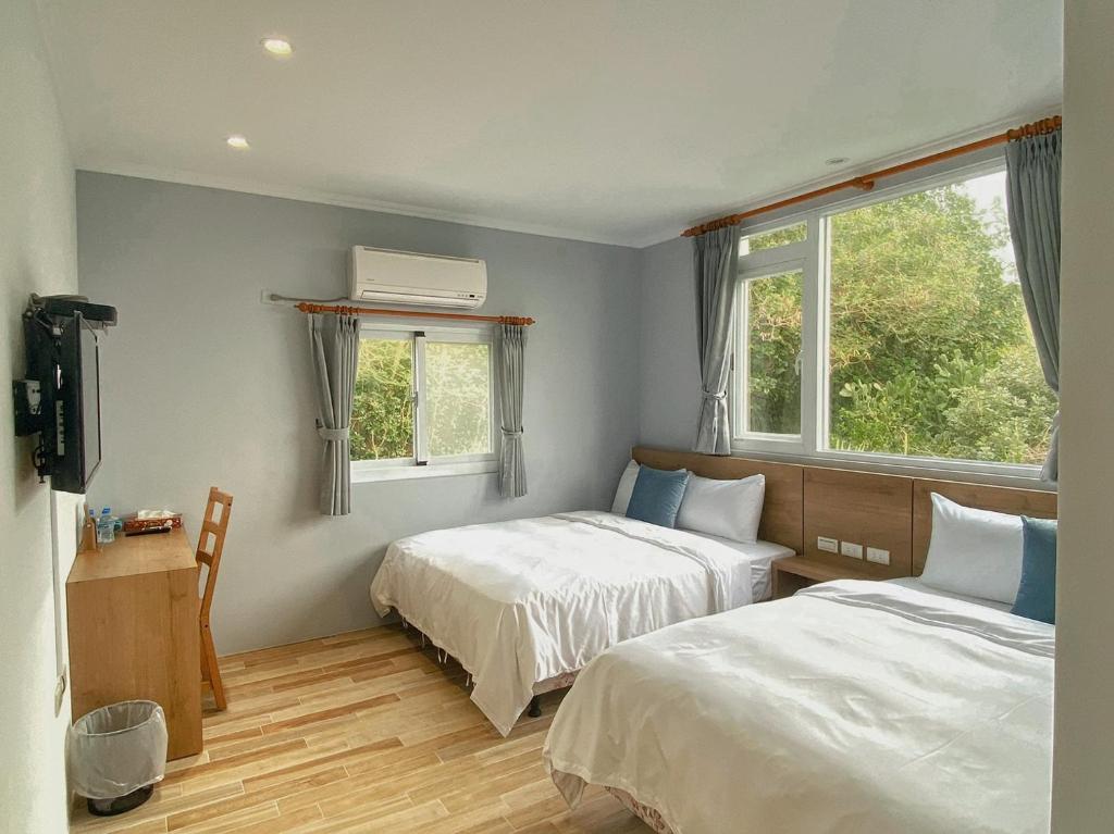 two beds in a room with two windows at 純粹Home 民宿 in Shui-wa-chüeh