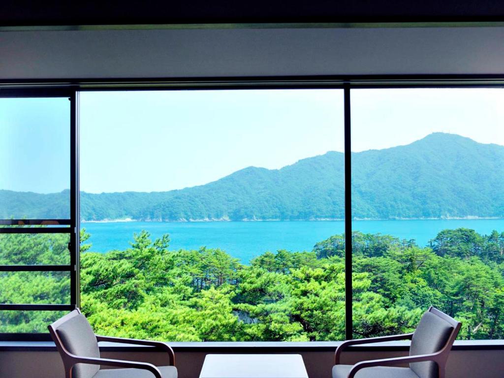 a room with a large window with a view of a lake at Jodogahama Park Hotel in Miyako