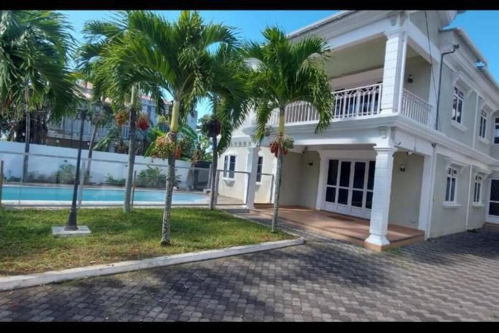 una gran casa blanca con palmeras y una piscina en Villa Palmira 6 suites avec piscine 5 min à pied de la plage Pereybere en Pereybere