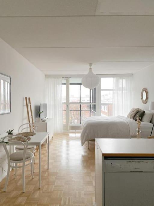 a white bedroom with a bed and a table and chairs at Modern and cozy apartment with Sauna in Espoo