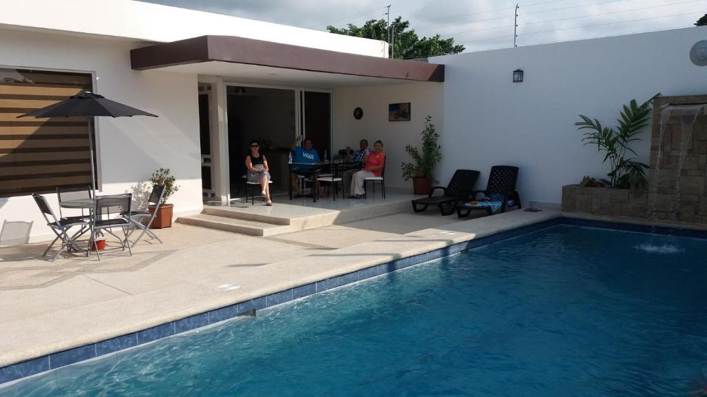 a group of people sitting at a table by a swimming pool at LA ESCONDIDA in Tonsupa