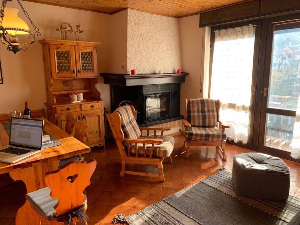 un soggiorno con scrivania, sedie e camino di La finestra sulle Dolomiti - The Window to the Dolomites a Fiera di Primiero